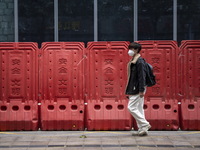 A man wearing a face mask walks pass barricades on January 8, 2023 in Shenzhen, China. China today lifts its requirement for inbound travele...