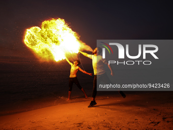 Palestinian youths show skills with perform fire breathing on Gaza Beach during sunset, on January 11, 2023.  (