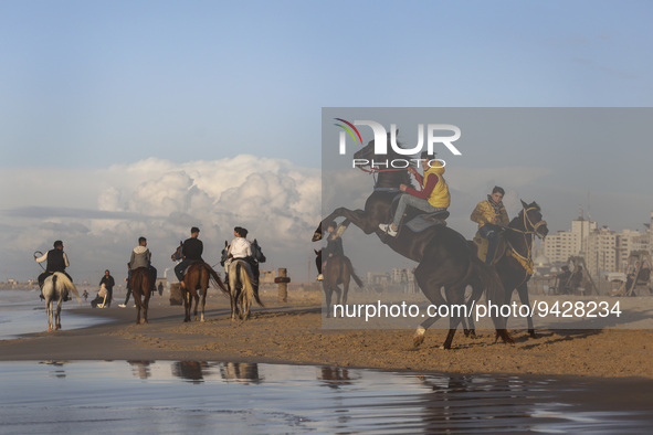 Palestinian youths on their horses take during sunset on the Gaza beach, on January 12, 2023.  