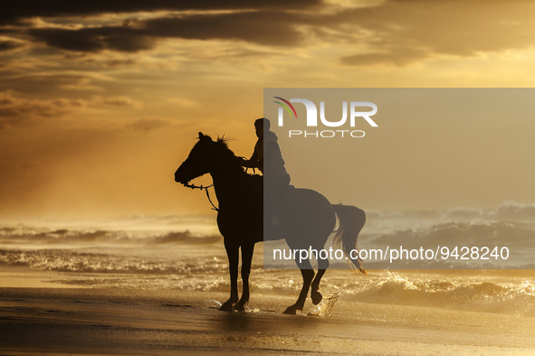 A Palestinian youth on his horse take during sunset on the Gaza beach, on January 12, 2023.  