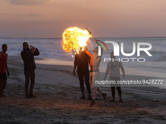 A Palestinian youth show his skills with perform fire breathing on Gaza Beach during sunset, on January 12, 2023.    (