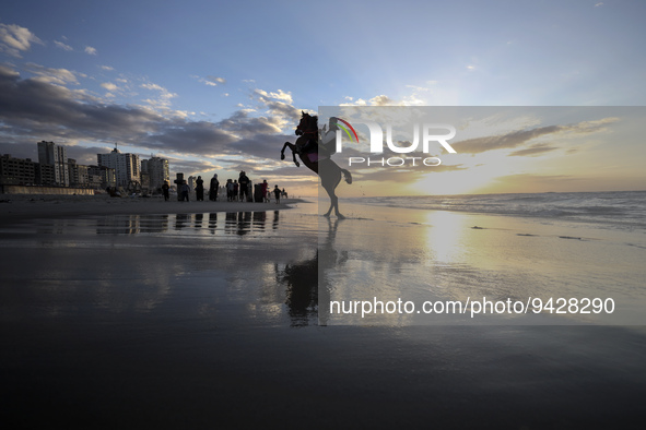 A Palestinian youth on his horse take during sunset on the Gaza beach, on January 12, 2023.  