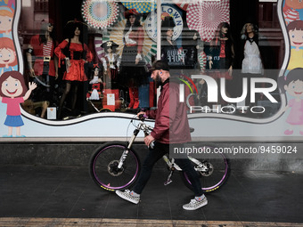 A man with his bicycle is passing in front of a store with carnival costumes in Athens, Greece on January 18, 2023. (