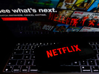 Netflix logo is displayed on a mobile phone screen with Netflix website in a background for illustration photo. Krakow, Poland on January 23...