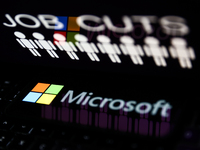 'Job cuts' sign and stick figures image displayed on a laptop screen and Microsoft logo displayed on a phone screen are seen in this illustr...