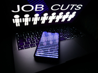 'Job cuts' sign and stick figures image displayed on a laptop screen and a binary code displayed on a phone screen are seen in this illustra...