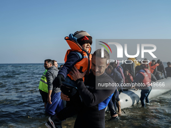 Volunteers help around 50 refugees and migrants to disembark from a vessel after their arrival from the Turkish coast to the northeastern Gr...
