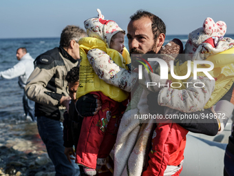 Volunteers help around 50 refugees and migrants to disembark from a vessel after their arrival from the Turkish coast to the northeastern Gr...