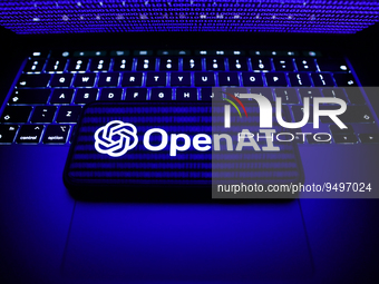A binary code displayed on a laptop screen, a laptop keyboard and OpenAI logo displayed on a phone screen are seen in this illustration phot...