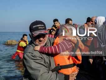 A man holds her child on a beach near to the town of Mytilene after crossing a part of the Aegean sea on a dinghy, with other refugees and m...