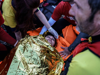 Spanish Lifeguards assists an injured woman lying on shore after she arrived with other migrants and refugees on the Greek island of Lesbos...