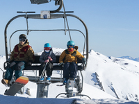 A father with his children on the chairlift to access the top of the slopes of the ski and mountain resort of Alto Campoo or Branavieja whic...
