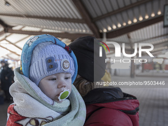 A mother who just arrived in Poland is holding her baby in a blanket. War refugees from Ukraine arrive at Przemysl railway station and get w...
