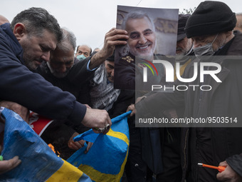 Iranian worshippers burn a national flag of Sweden as one of them holds a portrait of former commander of the Islamic Revolutionary Guard Co...