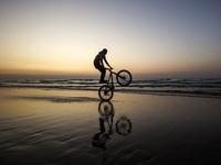 A Palestinian boy on his bike in front of Gaza beach during sunset, on February 10, 2023. (