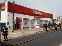 Firefighters put out a burning Auchan supermarket in Dakar on March 16, 2023. Supporters of Ousmane Sonko came out to protest and show suppo...