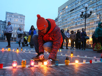 A man places a candle during a memorial commemorative rally for people killed a year ago inside the Mariupol Drama Theatre building by Russi...