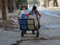 A Syrian boy pushes a cart with jerrycans filled with water in Aleppo on December 30, 2015 as residents of the northern city suffer constant...