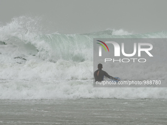 A surfer enters the Mediterranean Sea on a stormy weather in the coastal city Herzliya, North of Tel-Aviv on January 08, 2016.  (