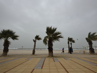 An Israeli girls runs at the beach on a stormy weather day in the coastal city Herzliya, North of Tel-Aviv on January 08, 2016.  (