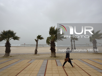 An Israeli woman walks barefoot at the beach on a stormy weather day in the coastal city Herzliya, North of Tel-Aviv on January 08, 2016.  (