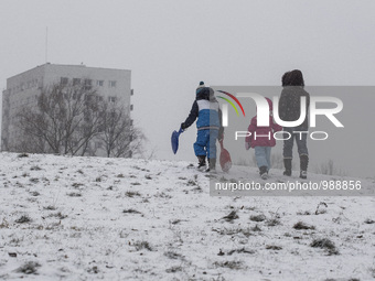 Mother with two children goes sliding down n a small hill next to the house, 08, January, 2016, Warsaw, Poland (