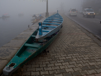 SRINAGAR, INDIAN ADMINISTERED KASHMIR, INDIA - JANUARY 13: Traffic plying on a road with their lights on during a cold foggy day on January...