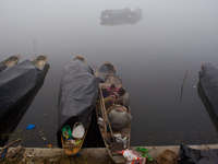 SRINAGAR, INDIAN ADMINISTERED KASHMIR, INDIA - JANUARY 13: A family of Kashmir fishermen rest in their boat during a cold foggy day on Janua...
