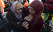 A volunteer is helping a refugee to leave the dinghy, as another dinghy with over 20 refug...