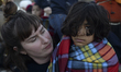 A volunteer is holding a young refugee after another dinghy with over 20 refugees arrives...
