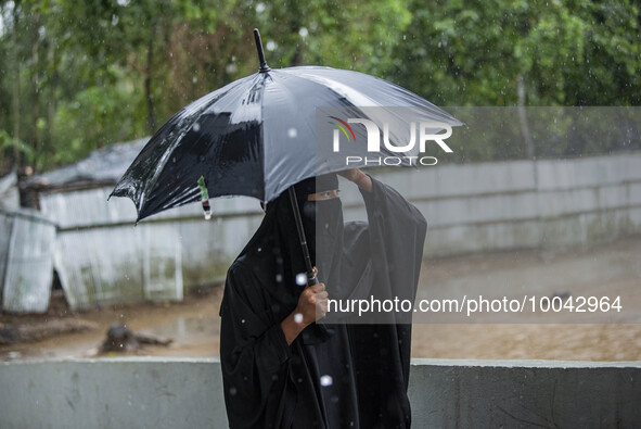 A woman move to take shelter in the Cyclone Shelter on Shahpori island on the outskirts of Teknaf, on May 14, 2023, ahead of Cyclone Mocha's...