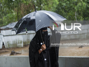 A woman move to take shelter in the Cyclone Shelter on Shahpori island on the outskirts of Teknaf, on May 14, 2023, ahead of Cyclone Mocha's...
