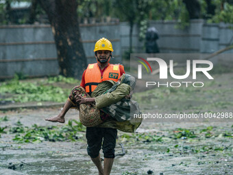 A volunteer carrying an old woman move to take shelter in the Cyclone Shelter on Shahpori island on the outskirts of Teknaf, on May 14, 2023...