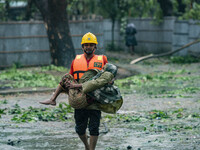 A volunteer carrying an old woman move to take shelter in the Cyclone Shelter on Shahpori island on the outskirts of Teknaf, on May 14, 2023...