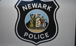 Newark police logo and signage on a Newark police vehicle at the crime scene. Two people s...