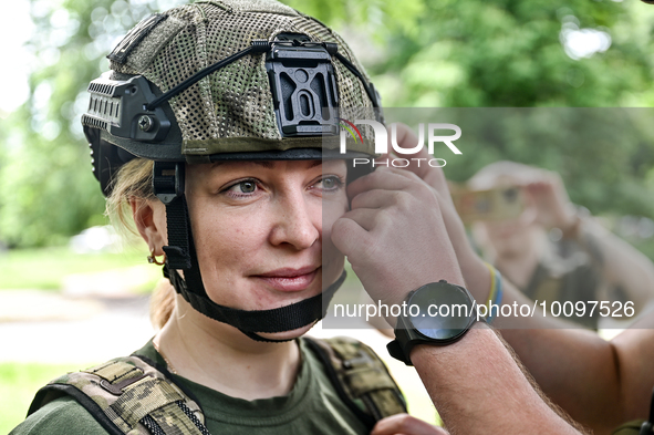 ZAPORIZHZHIA REGION, UKRAINE - MAY 28, 2023 - A servicewoman of the 128th Mountain Assault Brigade gets help in putting on a helmet before t...