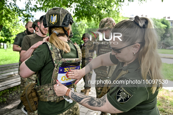 ZAPORIZHZHIA REGION, UKRAINE - MAY 28, 2023 - A servicewoman of the 128th Mountain Assault Brigade attaches a sticker with a number to a bul...