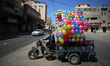 A Palestinian man rides tuk-tuk loaded with plastic footballs in Gaza City on May 31, 2023...