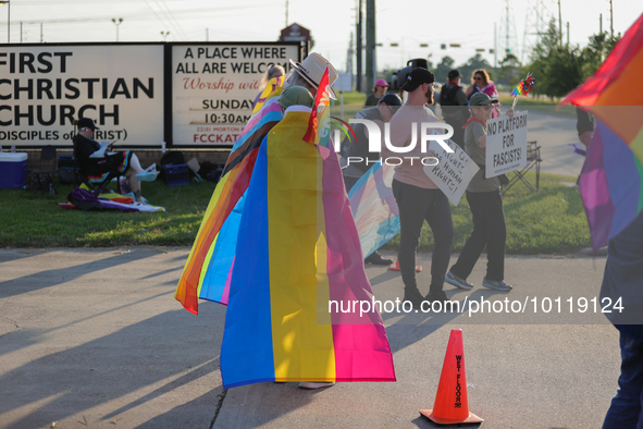 A pro-LGBTQ protestors hold signs and wear LGBTQ pride flags in support of First Christian Church's Trans Youth program in Katy, Texas on Ju...