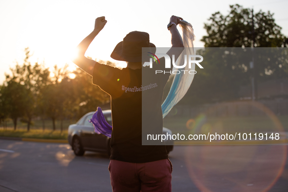 A pro-LGBTQ protestor waves a flag and dances in support of First Christian Church in Katy, Texas on June 3, 2023. They wear a shirt from a...