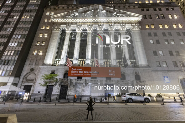 Night view of the illuminated exterior of New York Stock Exchange with American flags. NYSE building has the style of classical architecture...