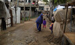 A Palestinian woman removing a rain water away from their houses on a rainy day of Beit La...