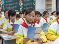 Pupils read publicity materials on fraud prevention, June 19, 2023, Nantong, Jiangsu Province, China. (