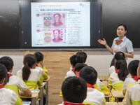A staff member of China Construction Bank publicized anti fake RMB knowledge to students in Nantong, Jiangsu Province, China, on June 19, 20...