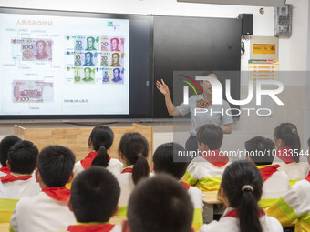 A staff member of China Construction Bank publicized anti fake RMB knowledge to students in Nantong, Jiangsu Province, China, on June 19, 20...