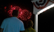 People watch a fireworks display in celebration of Independence Day from the boardwalk on...