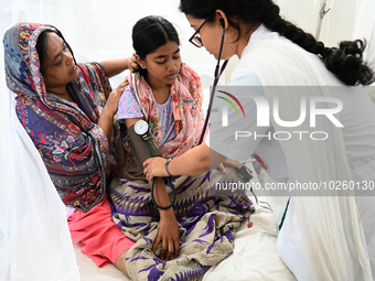 A Doctor treats a patient covered with mosquito nets who are suffering from dengue fever rest inside the 'Shaheed Suhrawardy' Medical Collea...