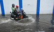 Commuters and office goers are seen making their way through a flooded road in Kolkata , I...