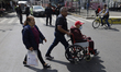 A person in a wheelchair is helped by a person while tenants block Avenida Tlahuac in Mexi...