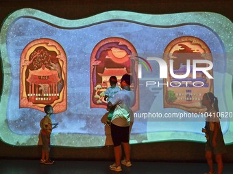 Visitors take part in an interactive game at the ''Time and Space Tunnel'' pavilion of Qingzhou Ancient City Scenic spot in East China's Sha...